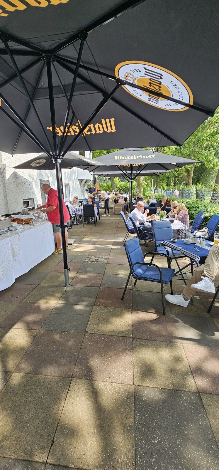 Gäste auf der Terrasse der Schifferstube unter Sonnenschirmen