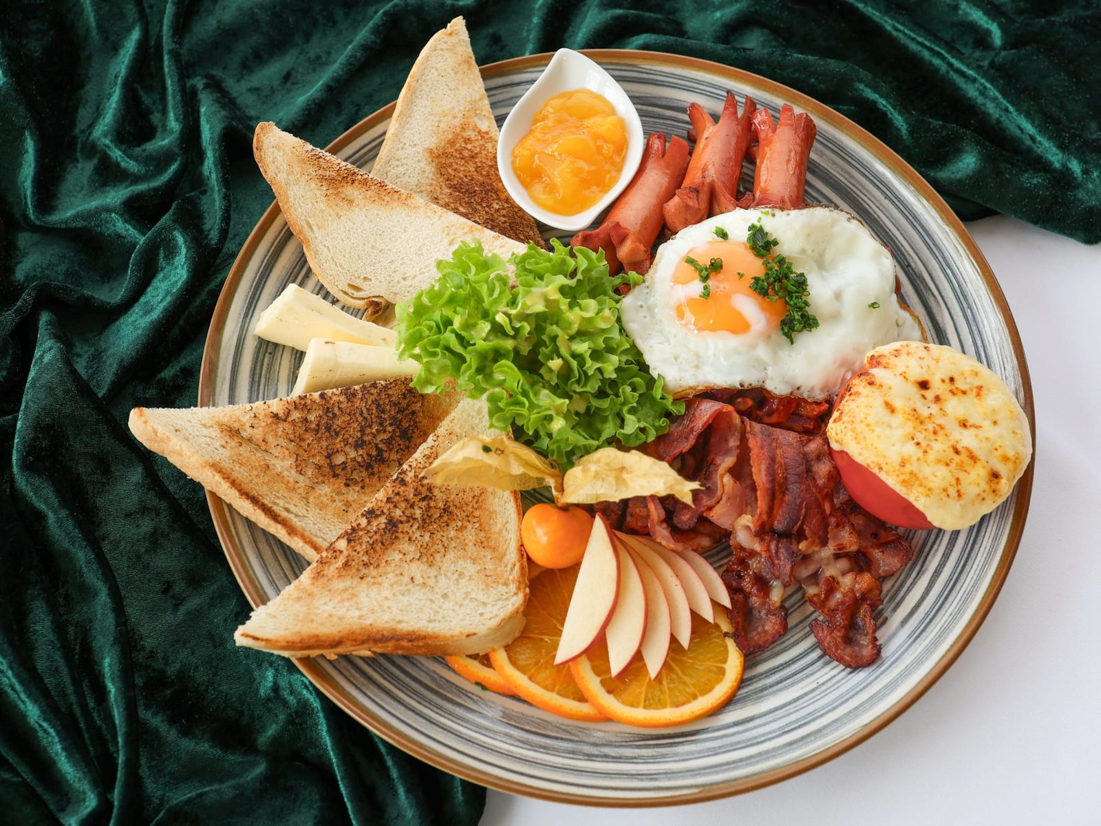 Reichhaltiger Frühstücksteller mit Toast, Ei, Bacon und Obst