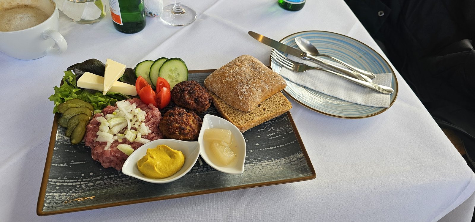 Herzhafter Frühstücksteller mit Hackfleisch, gebratenen Buletten, Gewürzgurke und Brötchen