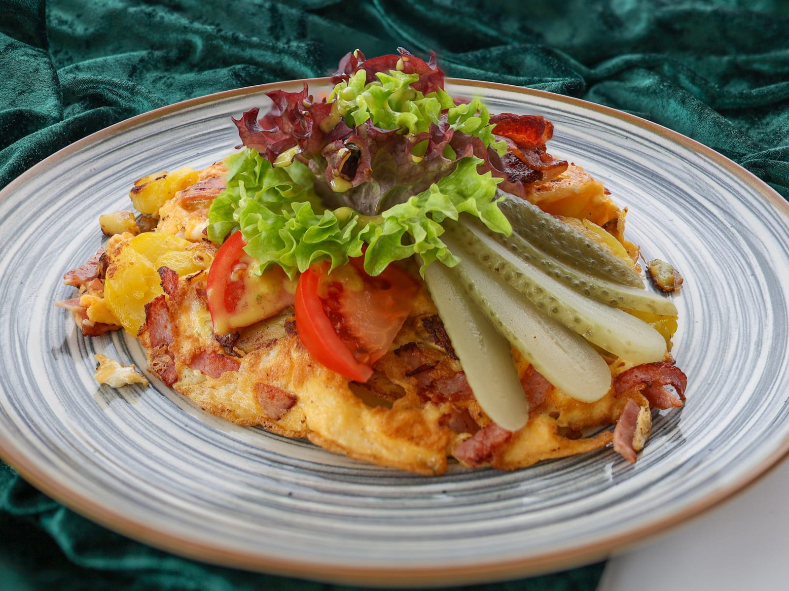 Omelett mit Bratkartoffeln, Speck, Tomate und frischem Salat